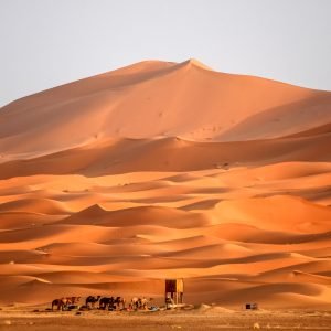 Berber homes at the foot of gigantic and stunning sand dunes of Sahara desert in Merzouga, Morocco